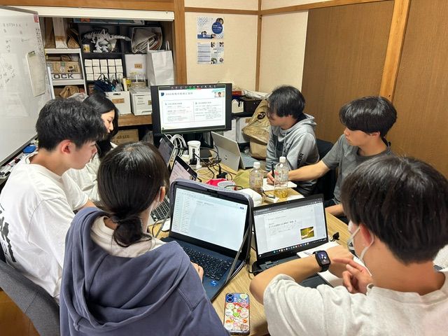 定例会でノートパソコンを囲んで話し合う学生スタッフ